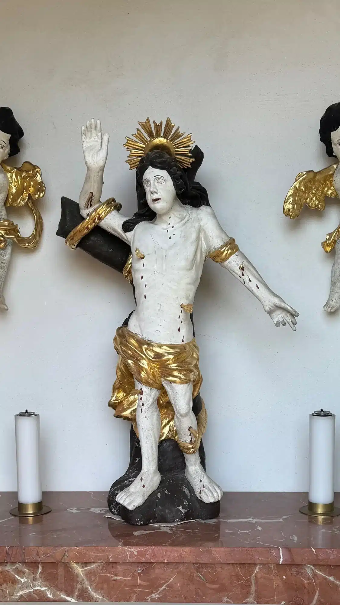 Übermalte, beschädigte Holzfigur des hl. Sebastian vor dem Entlacken